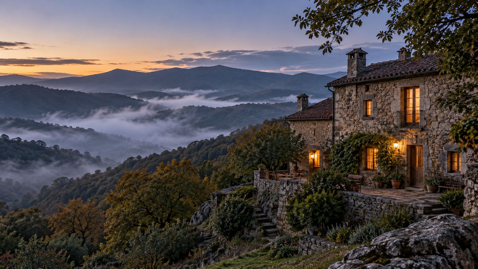 La casona de piedra al atardecer, con niebla en el valle